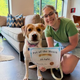 a person and a dog holding a pet of the month sign