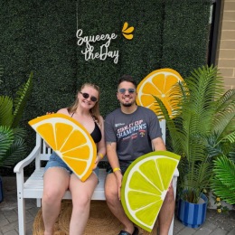 people sitting down holding large pieces of art that look like fruit 